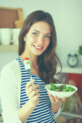 Young woman eating salad and holding a mixed