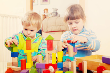 Two  tranquil children playing with wooden toys