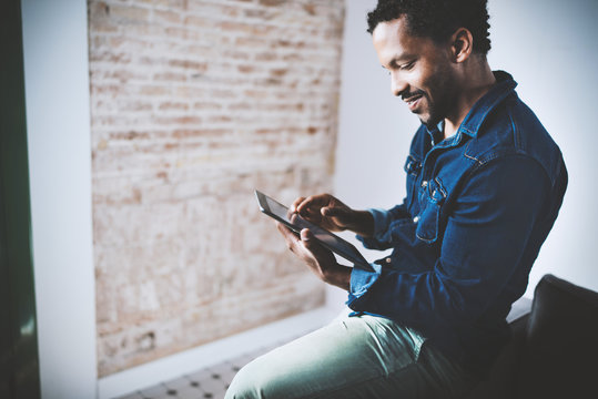 Musing Bearded African American Freelancer Touching Display Of Digital Tablet While Working In New Project At Home.Black Businessman Looking For Information On Internet.Blurred,color Filter.