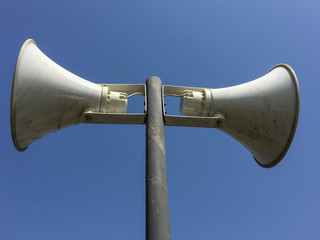 two loudspeakers on the pillar in blue sky background