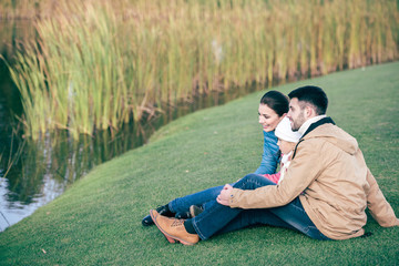 Fototapeta premium Smiling family sitting near lake