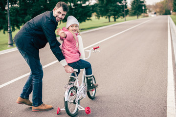 Father teaching daughter to ride bicycle