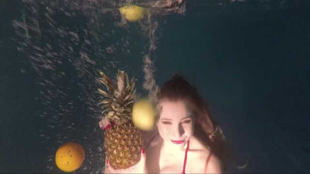 Beautiful girl with pineapple in hands under water