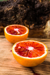 Sweet and fresh blood orange halves on wooden cutting board.