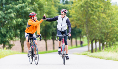 Rennradfahrer klatschen am Ziel nach Sport und Fitness workout ab