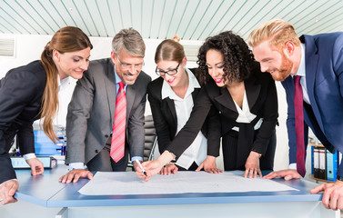 Gruppe Geschäftsleute lehnt sich über Schreibtisch und analysiert Graphen