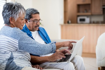 Senior couple using laptop in living room