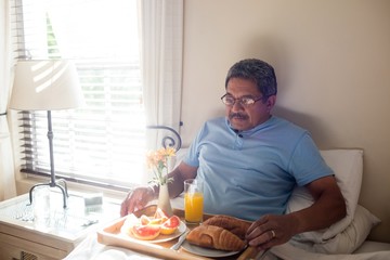 Senior man having breakfast on bed