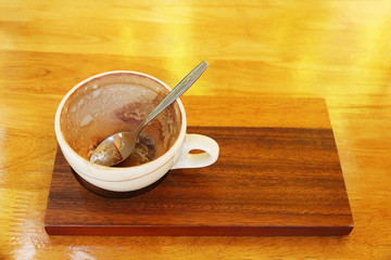 empty coffee cup with spoon on wooden plate