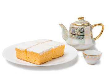 Coconut cream cake with teapot and tea glass on white background