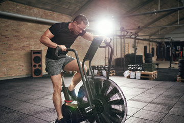 Obraz na płótnie Canvas Muscular male working out on cycling machine