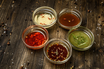 Sauces in glass bowls on wooden dark background