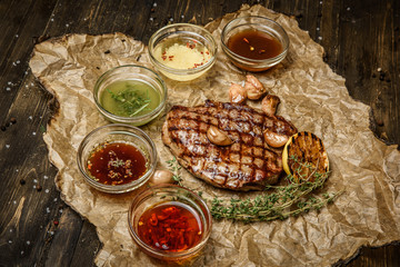 grilled steak with different sauces, on parchment. vertical top view