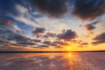 Sunset sky with clouds above salt lake. Beautiful sunny landscape.