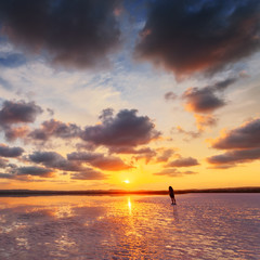 Naklejka na ściany i meble Beautiful sunset, sky with clouds above salt lake. Person take photo of scenic landscape.