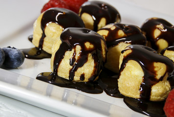 Delicious profiteroles with cream and chocolate glaze on a plate