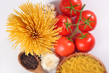 Uncooked Italian pasta, ripe tomatoes branch and black pepper on
