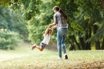 Mother and daughter playing circling around at the park on beautiful morning.