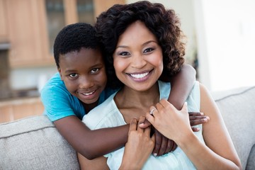 Portrait of mother and son embracing each other in living room
