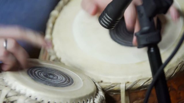Close-up of man playing the tabla drum. A young man plays his djembe drum. Closeup man's hands drumming out beat on skin-covered bongo hand drum