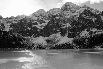 Black and white panorama of winter mountains. view from frozen lake