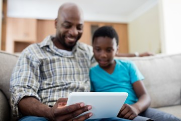 Father and son using digital tablet in living room