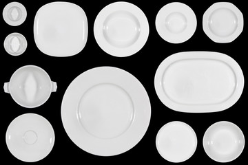 Variety of white plates of different sizes and shapes on black background directly from above