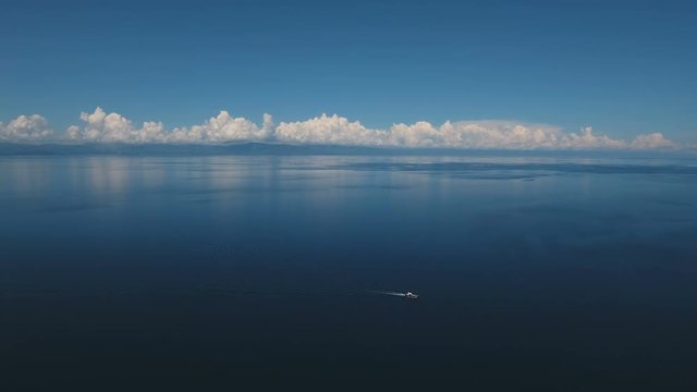 Aerial view of motor boat in sea. Aerial image of motorboat floating in a turquoise blue sea water. Sea landscape with wake of small fast motorboat. Tropical landscape. Philippines, Cebu. 4K video
