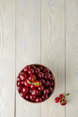 ripe cherries in a bowl on a textured wooden background, view from above