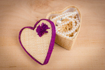 Elegant valentine card with white pearls and gift box shaped of heart on wooden background