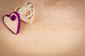 Elegant valentine background with white pearls and gift box shaped of heart on wooden background. Empty space for text