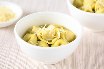 Traditional Italian Tortellini in Brodo (broth) soup with grated cheese on top, photographed with natural light (Selective Focus, Focus in the middle of the first bowl)