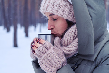 Tender calm young woman tasting tea from cup in a snowy forest