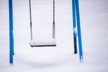 Winter. Children's swing covered with snow. 