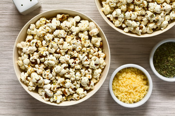 Homemade fresh savory popcorn with cheese, garlic and dried oregano in bowls, photographed overhead with natural light (Selective Focus, Focus on the top of the popcorn)