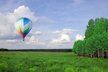 Balloons fly over the green fields, hills in summer