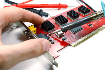 The installation of repair part on the DVR motherboard with a soldering iron on a white background