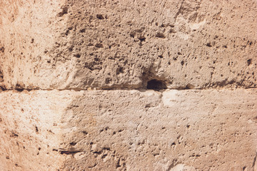 Texture of ancient wall. Damaged stone with holes. Touch the history.