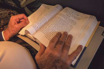 Male hands and opened book. Pages with text. Source of wisdom.