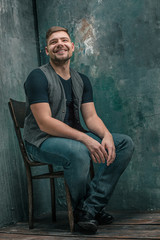 Portrait of smiling happy man sitting on the chair in studio