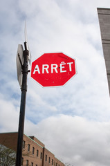 Stop sign in downtown Montreal on a cloudy spring day.  Stop in French.