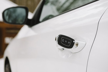Car keys in white door lock closeup with copy space. Opening car door with key
