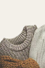 tinted image three warm sweaters on lighte background, vertical