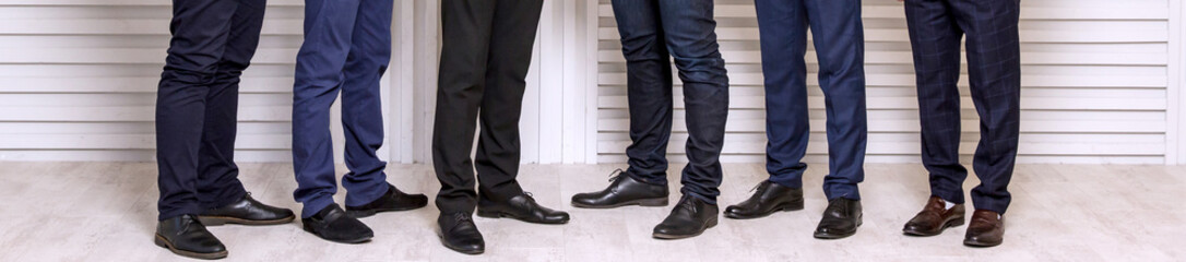 Six men's feet in black leather shoes