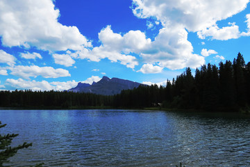 A distant landscape with a crystal clear lake surrounded by nature and a mountain. Banff, Alberta, Canada.