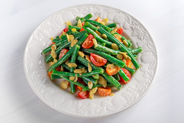 Green beans salad with bruschettas, Red, Yellow Tomatoes and flaked almond on white plate