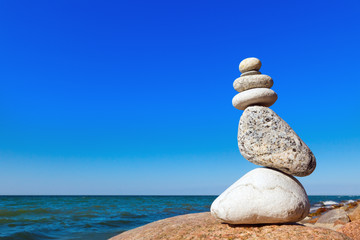 balance of white stones on a background of blue sky and sea
