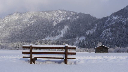 Sitzbank im Schnee und blick auf die Berge