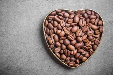 Coffee seeds in heart shape on gray rocky surface.