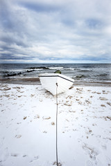 Germany, Usedom, Bansin, Imperial Spa (Kaiserbad): White fishing boat on snowy icy beach with seabridge in the background and dramatic clouds.